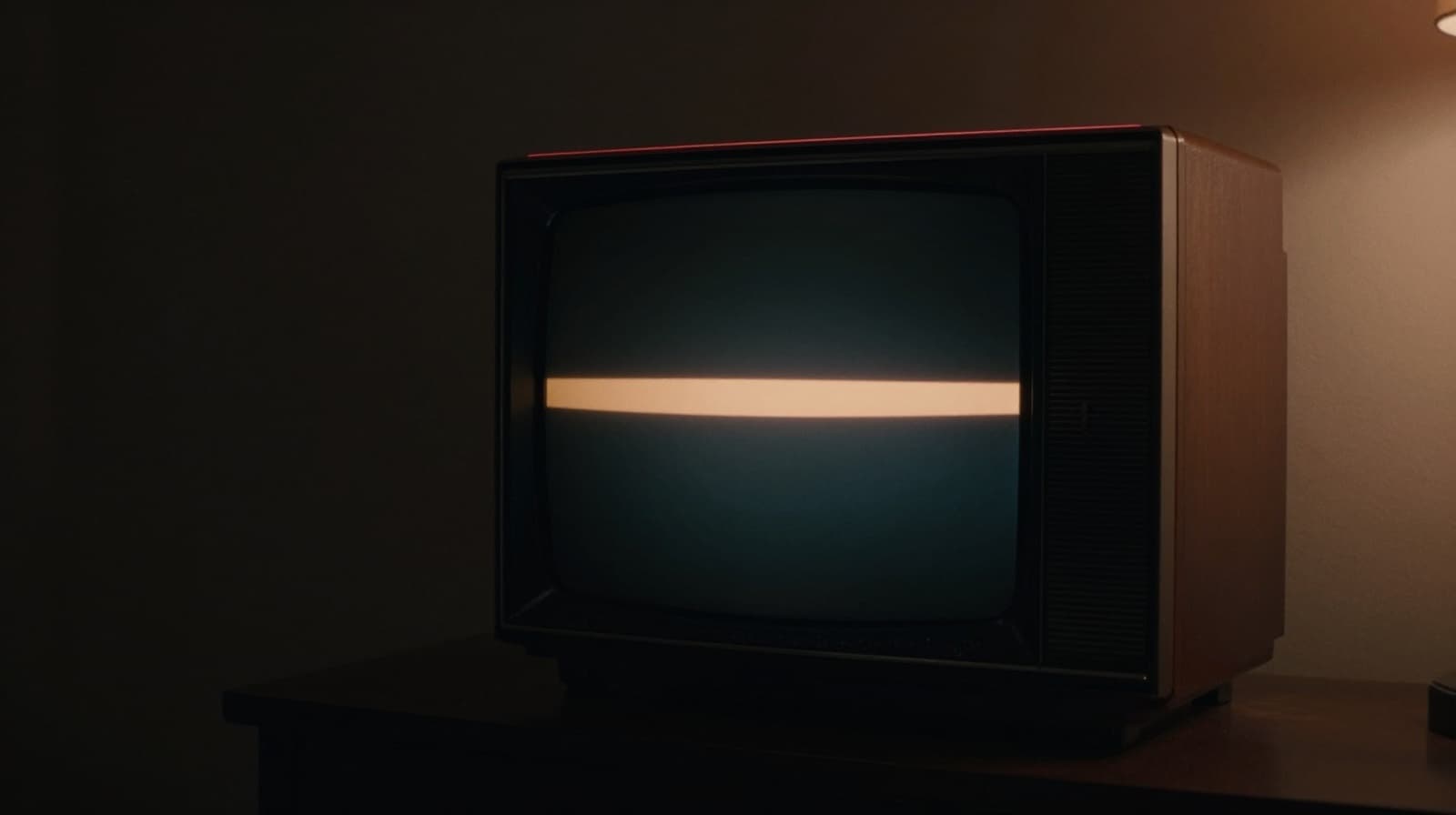 Vintage CRT televizor u tamnoj sobi, jedna topla amber traka preko ekrana kao caption.